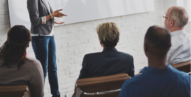 A business training session facilitated by a woman shown from the chest area down.