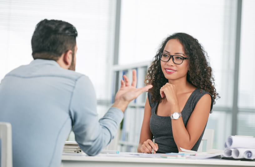 A Caucasian man interviewing a Latino woman for an office position.