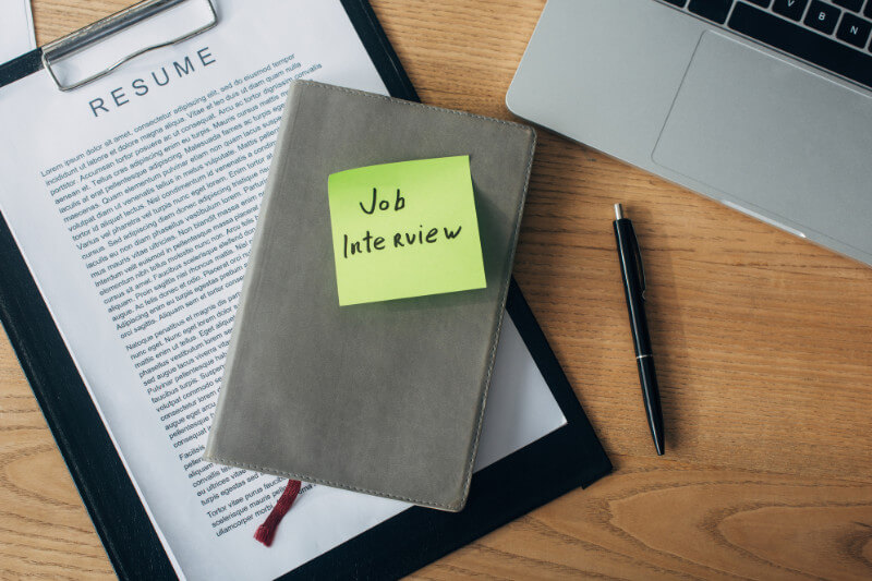 A resume on a clipboard and job interviewer notes.