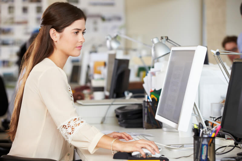 A young woman working at a computer in an office.