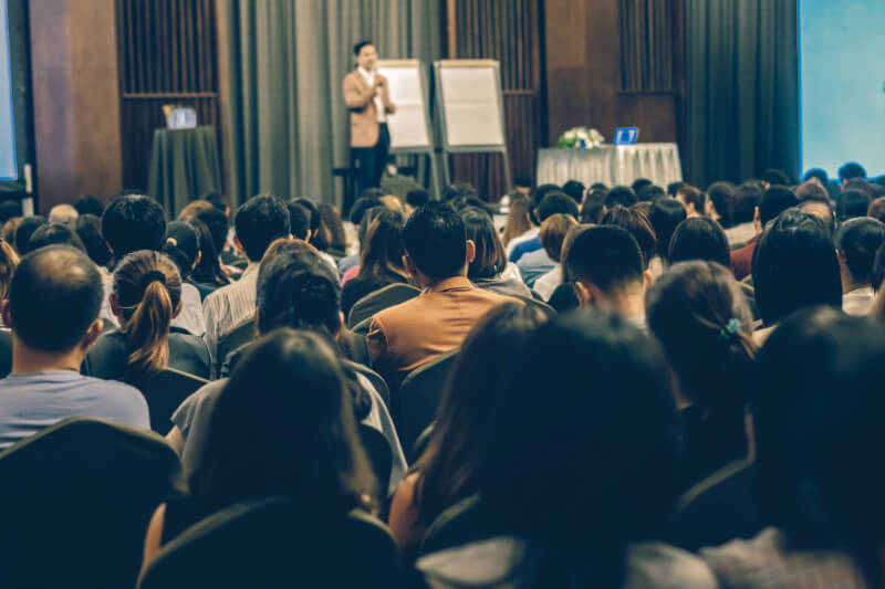 A speaker giving a presentation to a crowd at a conference.